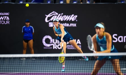 Storm Hunter serves with Elisa Mertens waiting at the net in the foreground