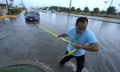 Mon Lun pulls a strap to his water stalled car before towing it out of receding flood waters in Dallas, on Monday.