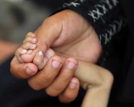 A close-up over a small child’s hand gripping on to the thumb of an adult.