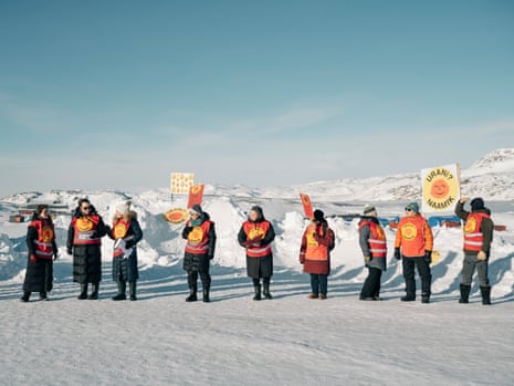 people wearing orange hi vis jackets and holding signs in a snowy background