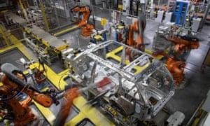 Robotic systems work on the chassis of a car during an automated stage of production at the Jaguar Land Rover factory in Solihull.