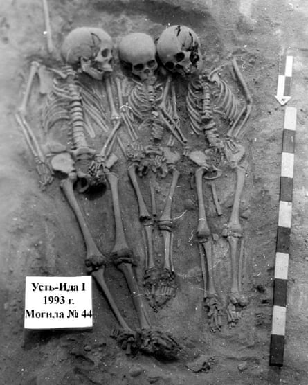 Three skeletons beside one another in a grave