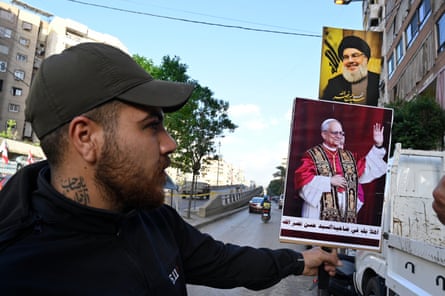 A man holds up a placard featuring Pope Leo and the late Hezbollah leader Hassan Nasrallah