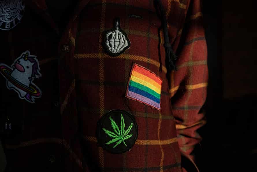 Closeup of a coat with a rainbow flag and other badges sewn on it. 