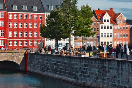 People perusing antiques and other objects by a canal with old attractive town houses behind them