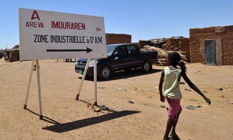 A resident walking past Areva's uranium symbol in a village near Arlit, Niger