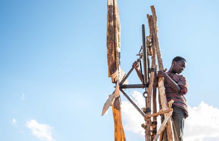 A boiy, played by Maxwell Simba, climbing on a homemade windmill in The Boy Who Harnessed the Wind