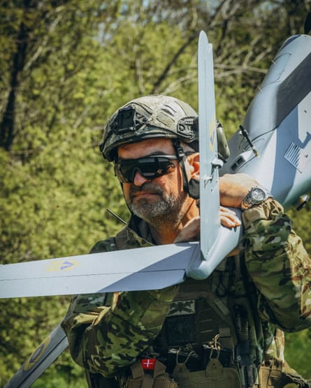 A soldier carrying a fan-tailed drone over his shoulder