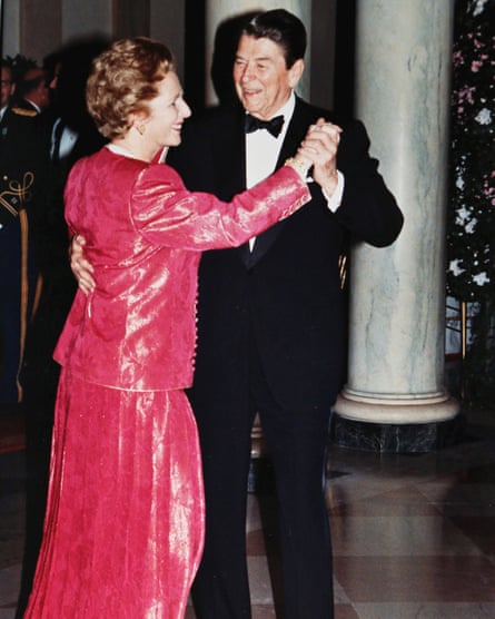Margaret Thatcher in a red matching jacket and skirt dances with Ronald Reagan in a tuxedo