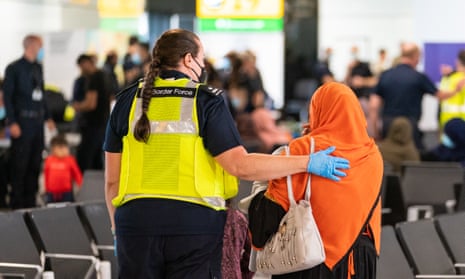 A UK Border Force staff member helps an Afghan evacuee at Heathrow airport.