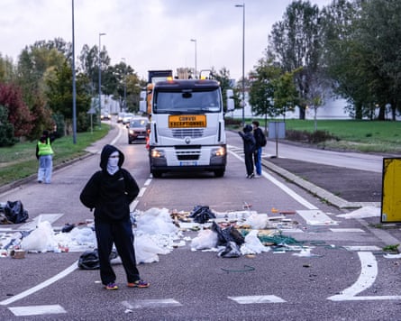 A protester guards a barrier made of rubble strewn across the road