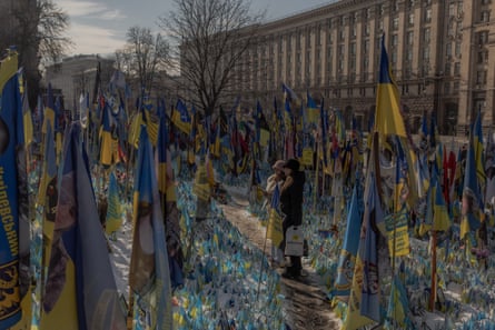 furled blue and yellow Ukrainian flags at a makeshift memorial in Independence Square in front of a large stone building