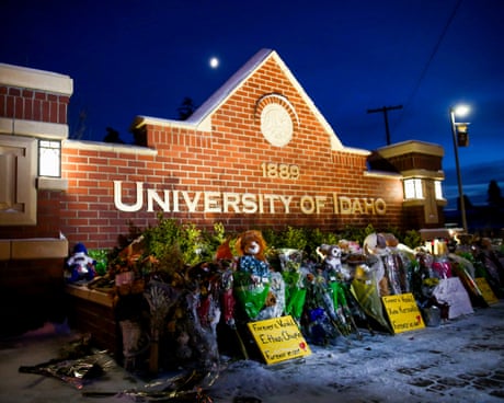 Rows of bouquets against a brick University of Idaho sign at night.