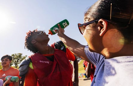 une femme verse de l'eau d'une bouteille dans la bouche d'un joueur de football