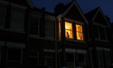A house in darkness with Kate Edgley standing in the one lit upstairs window