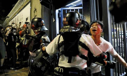 A man is taken away by policemen after attacked by protesters outside Kwai Chung police station in Hong Kong.