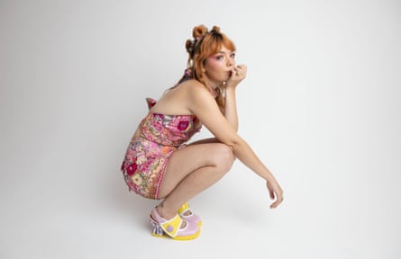 Hayden crouches while wearing an embellished halterneck and miniskirt