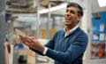 Rishi Sunak smiling and holding up a plate in a factory.