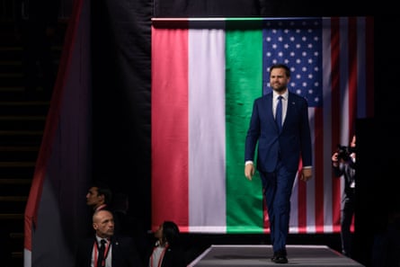 Vance walking onstage in front of US and Hungary flags