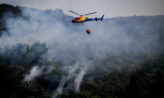 A firefighting helicopter flies over burning forest near Bustelo in Portugal