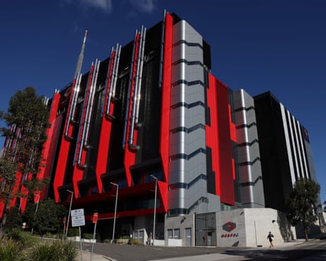 A modern building with bold red, black, and silver panels under a clear blue sky