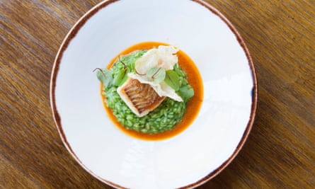 Green herb risotto and brill on a round white plate.