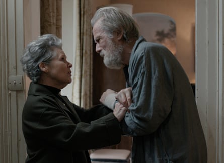 A woman with grey hair clasping the hands of a man with grey hair and a beard