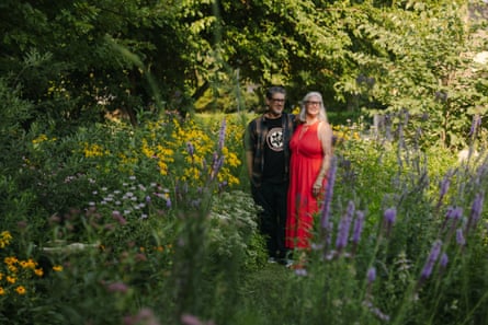 Crystal Fritz and James McGuire pose for a portrait in their yard, surrounded by dense, healthy looking plants.