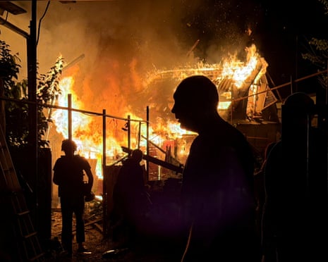 Residents look at a private house that burns after an overnight Russian drone strike, amid Russia's attack on Ukraine, in Zaporizhzhia, Ukraine.