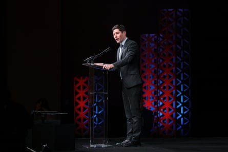 a man in a suit speaks into a microphone