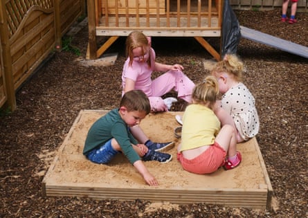 Four children playing in a small sandpit