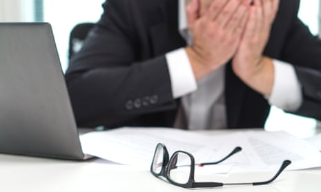 Stressed businessman covering face with hands in office