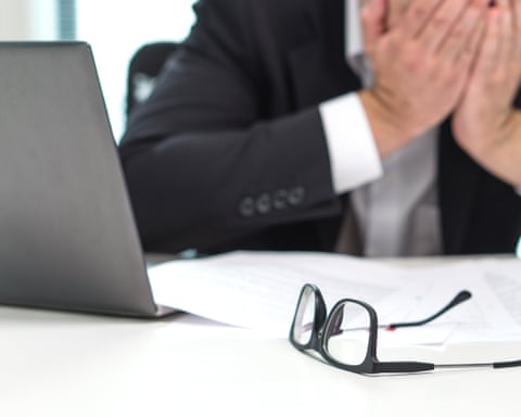 Stressed business man covering face with hands in office.