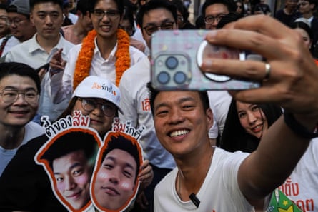 Natthaphong Ruengpanyawut, the leader of the People’s Party and a candidate for prime minister, poses for a selfie with supporters during an election campaign event in Bangkok