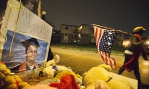 A woman carries an American flag past a high school graduation photo of Michael Brown at a memorial in Ferguson.