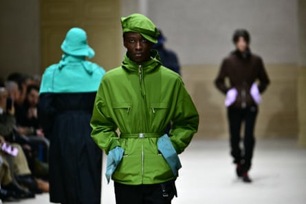 A male model wearing a bright green cagoule with a matching beret