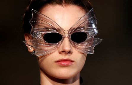 A model wears a Venetian mask-style mask.