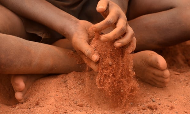 A young Aboriginal boy plays in the red sand