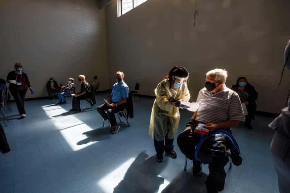 Nurse Priscilla Policar fills in paper work with community members inside a gymnasium at St Fidelis Parish.