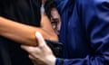 A young girl is held tight as she weeps