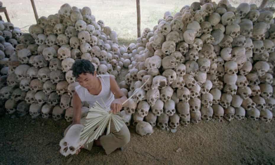 A man cleans a skull near a mass grave at the Chaung Ek torture camp run by the Khmer Rouge.