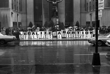 Black-and-white image of people standing in a row holding signs of one letter each that together spell out “legalize abortion”.