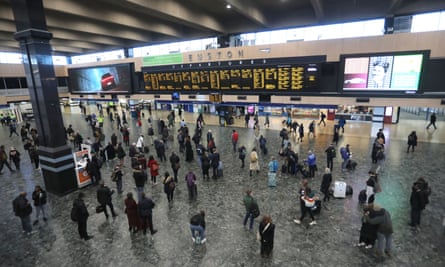 Euston station concourse with travellers looking up at the departure board
