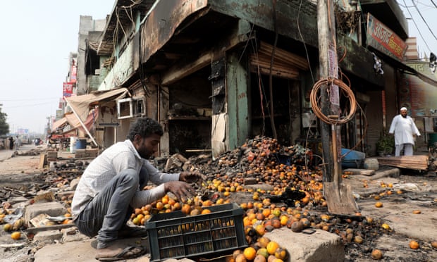 A man collects the remains of damaged fruit in a row of burnt-out shops in north-east Delhi on 28 February.