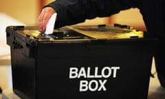 A voter places their voting paper in a large black ballot box