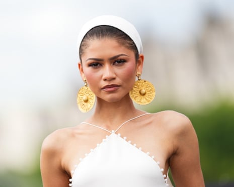 Zendaya in a white sleeveless dress with golden disc-shaped earrings