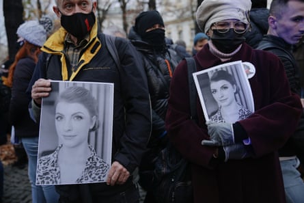 Protesters hold photos of a young woman