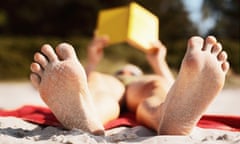 Woman lying on beach reading book