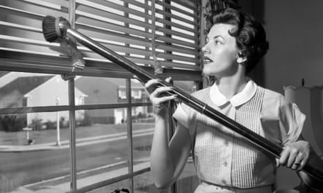 1950s shot of a woman vacuuming venetian blinds.