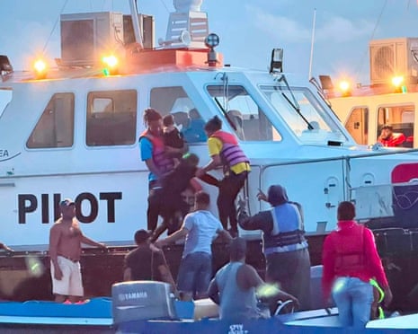 Rescuers pull passengers, including a small child, to safety aboard a white ship